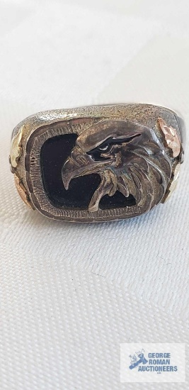 Silver colored ring with eagle, black gemstone behind, two-toned leaves on side, marked 925 and 12K,