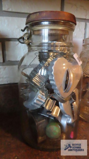Glass milk jug with metal handle, filled with cookie cutters