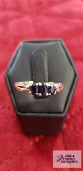 Gold colored ring with three dark blue stones and two clear gemstone chips, marked 10KP, approximate