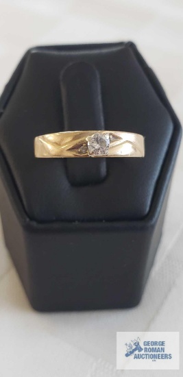 Gold colored band engagement like ring with clear gemstone and two smaller gemstones, marked Magic