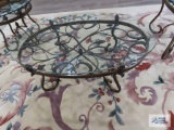 Glass top coffee table with ornate metal base. 52