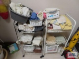 Two rolling metal storage racks including hand towels, washcloths