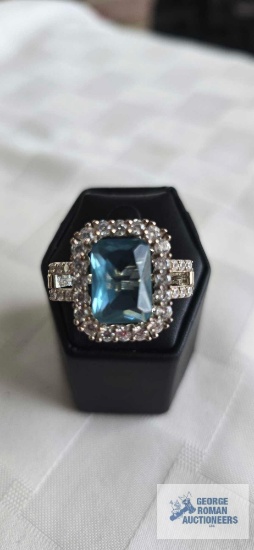 Silver colored ring with large pale blue stone and surrounding clear gemstones, marked 925, 7.5 G,