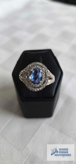Silver colored ring with blue stone surrounded by clear gemstones, marked 925, 4.8 G, size 8.5