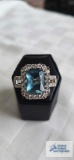 Silver colored ring with large pale blue stone and surrounding clear gemstones, marked 925, 7.5 G,