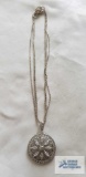 Silver colored pendant with clear gemstones, no markings found, on silver colored multi-strand