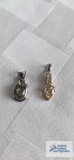 Silver colored pendant with pale green stone and silver colored pendant with yellow stones. Both