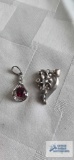 Silver colored floral pendant with clear stone, marked 925. Silver colored pendant with red stone,