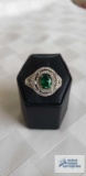 Silver colored ring with large green stone surrounded by clear gemstones, marked LNT 925 IN,