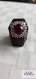 Silver colored ring with large red gemstone and surrounding clear gemstones, marked 18K HGE 10.5 G,