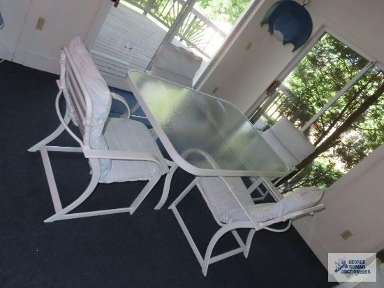 Glass top outdoor table with four armchairs. On first floor.