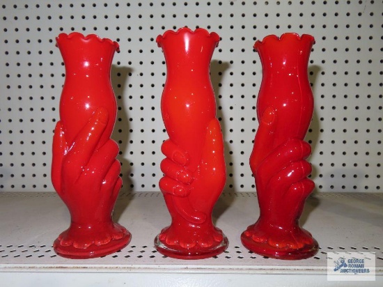 Three red glass hand held vases