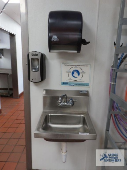 Stainless steel hand sink made by John Boos, includes soap dispenser and paper towel holder. Sink is