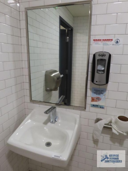 Bathroom sink with hanging mirror, soap dispenser, tissue paper dispenser, napkin dispenser, and