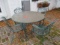 Round Green Metal Pebble Glass Top Table and Four Green Metal Mesh Chairs