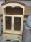 Cream Colored Curio Cabinet with Two Glass Shelves and Doors and Bottom Drawer.