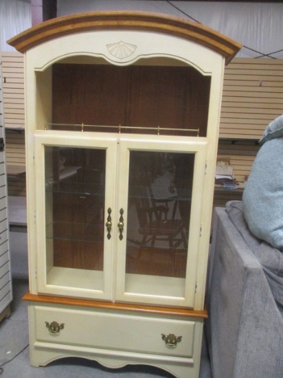 Cream Colored Curio Cabinet with Two Glass Shelves and Doors and Bottom Drawer.