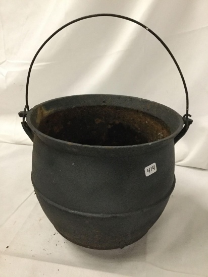Cast iron caldron with handle, used as flower pot and has crack in rim, one handle latch is broken,