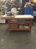 Large wood work table with some tools and pieces in the drawers with grease pump on top