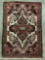 Vintage small wool rig, red tones with floral design - symmetrical ornate pattern