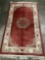 Thick wool rug with fringe, natural red tones with geometric and floral designs