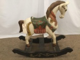 Antique wooden rocking horse with colorful painted adornments and dark base