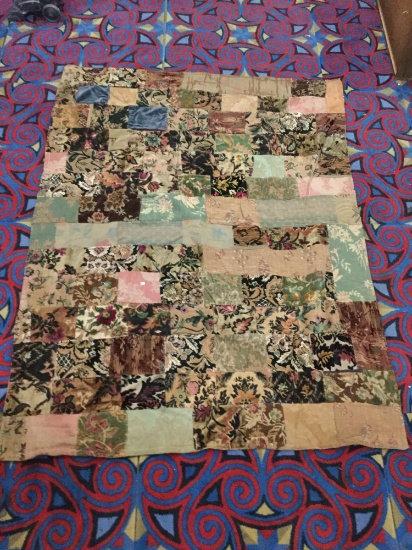Vintage hand made quilt feat. various floral patterns, and checkered with many fabrics