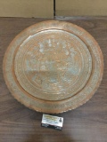 Asian metal plate featuring a ceremony scene. Measures approx 19.5x19.5 inches.