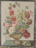 Woven framed tapestry of flowers in vase.