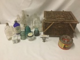 Wicker basket full of nine vintage bottles, three insulators, a coffee tin, and a tobacco tin