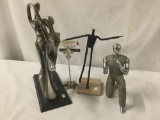 Collection of 3stTues of humans. Metal kneeling man, composite dancers, and wire man.