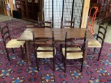 Antique wooden dining table with 6 matching ladder-back wicker seat chairs - dark finish