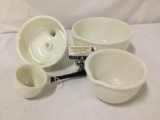 Collection of vintage milk glass mixing bowls and other kitchen tools.