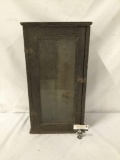 Antique medicine cabinet with glass window door and wooden shelves.