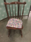 Vintage rocking chair with floral seat pad.