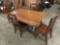 Vintage wood drop-leaf dining table with 4 wooden chairs, approx 38x61x30 inches.