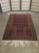 Small handwoven wool rug w/ fringe & colorful geometric patterns & fringe. Approx. 63x35 inches.