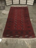 Long red handwoven wool rug w/stunning geometric patterns & fringe. Approx. 94x42 inches.