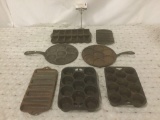 Seven vintage cast iron items, incl. muffin trays, silver dollar pans, corn trays, and more.