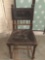 Antique carved wood court chair with tooled leather upholstery. Measures approx 36x20x16 inches.