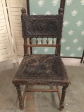 Antique carved wood court chair with tooled leather upholstery. Measures approx 36x20x16 inches.