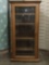 Wood curio/entertainment cabinet w/ 4 shelves & casters, approx. 26x18x51 inches.