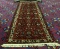 Red wool runner rug w/ fringe & colorful geometric designs. Approx. 120x40 inches.