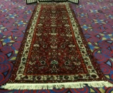 Red wool runner rug w/ fringe & colorful geometric designs. Approx. 120x40 inches.