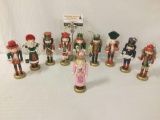 Ten painted wooden nutcrackers, many holding birds, approx. 7x2.5x2.5 inches each.