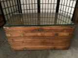 Vintage wood trunk/coffee table w/ thick glass top & brass hardware, approx. 21x41x21 inches.