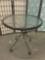 Glass top patio table with wicker accenting. Shows wear.