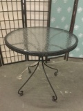 Glass top patio table with wicker accenting. Shows wear.