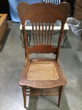 Vintage wood carved chair with woven wicker seat, approximately 20 x 41 x 19 in.