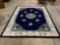 Large wool carpet w/ pink floral design, deep blue background, approx 108 x 142 in. Nice condition